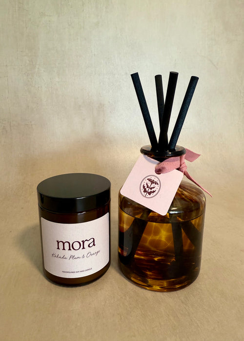 Candle and diffuser set with 'mora' branding on a beige background