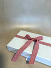 White gift box with a pink ribbon on a beige background