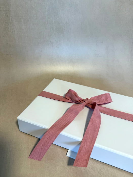White gift box with a pink ribbon on a beige background