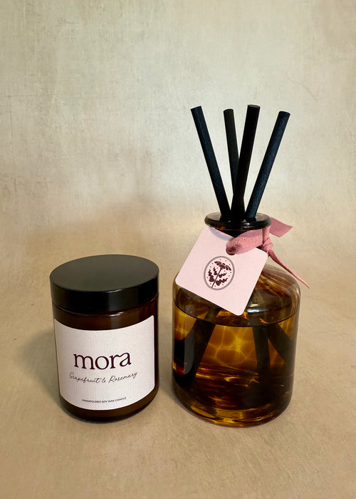 Candle and diffuser set with 'mora' branding on a beige background